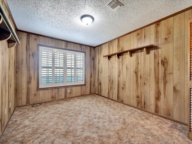 spare room featuring wood walls, light colored carpet, and a textured ceiling