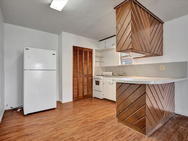 kitchen with white appliances, white cabinets, a textured ceiling, light hardwood / wood-style floors, and kitchen peninsula