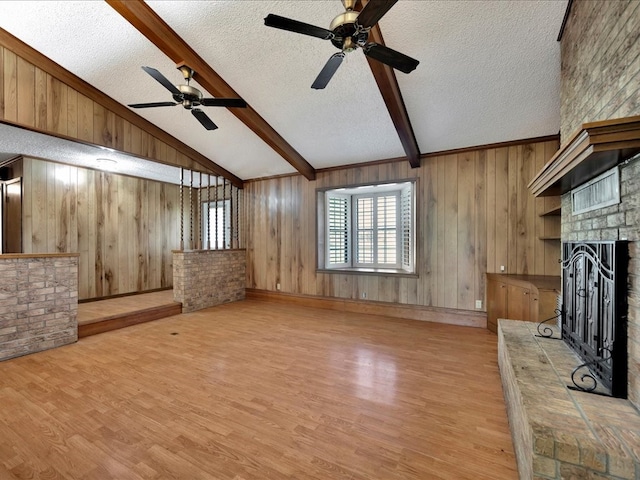 unfurnished living room with a textured ceiling, light hardwood / wood-style flooring, and wood walls