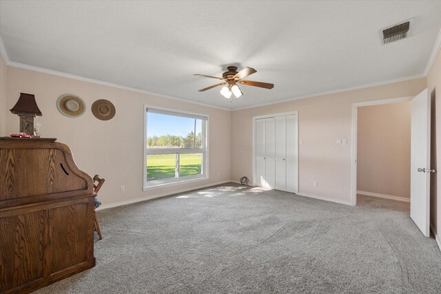 unfurnished bedroom with ceiling fan, crown molding, and light carpet