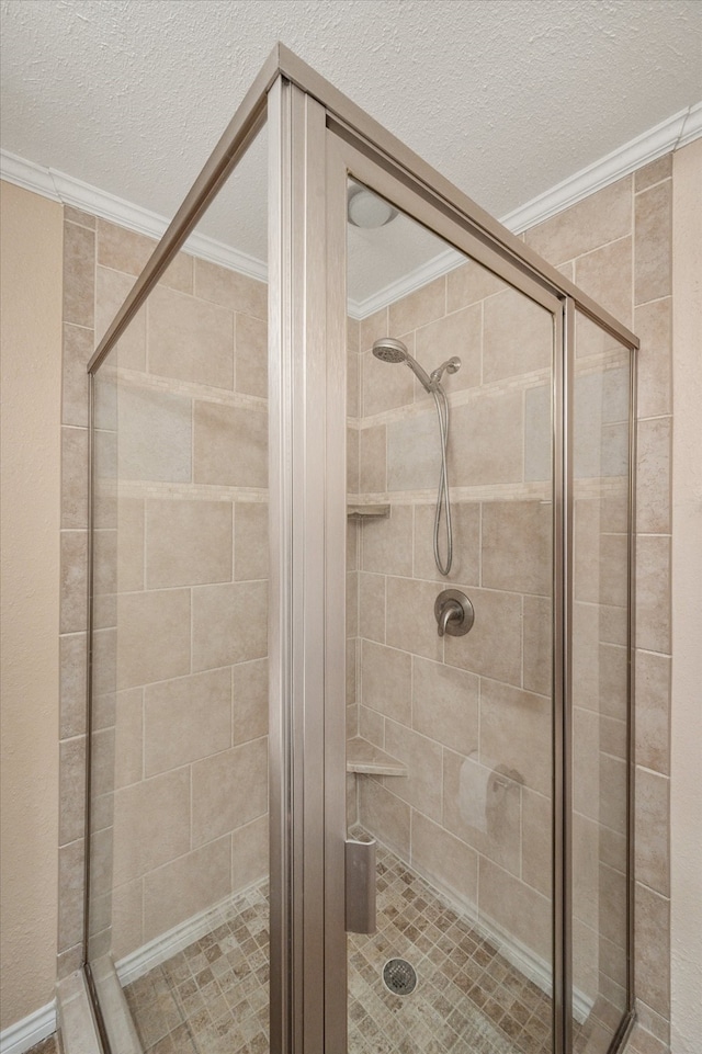 bathroom featuring a shower with shower door, ornamental molding, and a textured ceiling