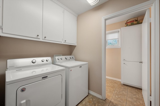 clothes washing area featuring washer and clothes dryer, cabinets, and light tile patterned floors