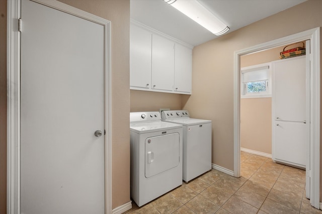 clothes washing area featuring cabinets, light tile patterned floors, and washing machine and clothes dryer