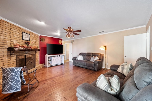 106 Coke St, Streetman, TX 75859 - living room with wood finished floors, a ceiling fan, ornamental molding, a brick fireplace, and baseboards