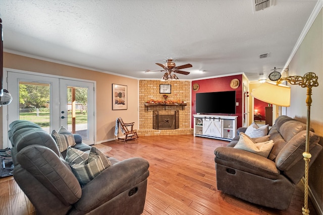 living room featuring crown molding, hardwood / wood-style flooring, ceiling fan, a fireplace, and a textured ceiling