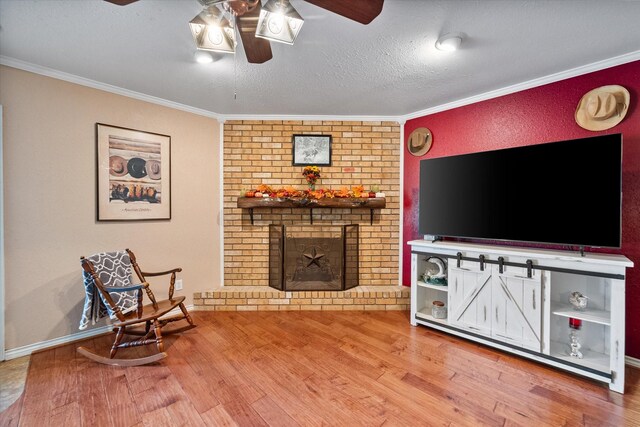 living room featuring a fireplace, hardwood / wood-style floors, ceiling fan, and crown molding