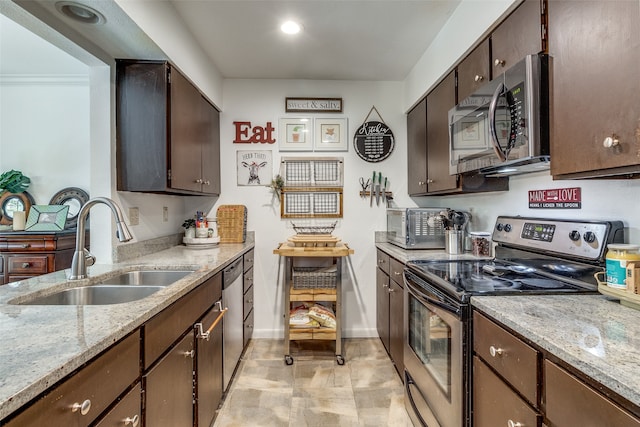 kitchen with appliances with stainless steel finishes, dark brown cabinetry, light stone counters, and sink