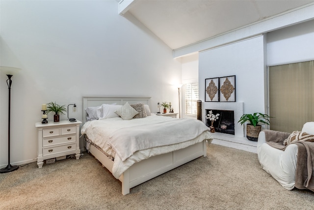 bedroom featuring a fireplace, light colored carpet, and high vaulted ceiling