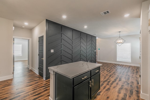 kitchen featuring decorative light fixtures, a center island, light stone countertops, and dark hardwood / wood-style flooring