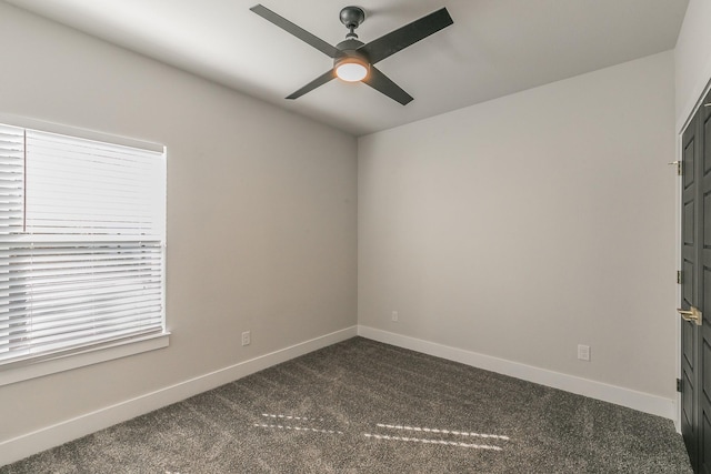 spare room with ceiling fan and dark colored carpet