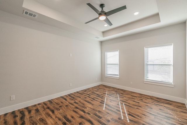 spare room featuring dark hardwood / wood-style floors, ceiling fan, and a raised ceiling