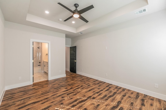 unfurnished bedroom with ceiling fan, light hardwood / wood-style flooring, ensuite bath, and a tray ceiling