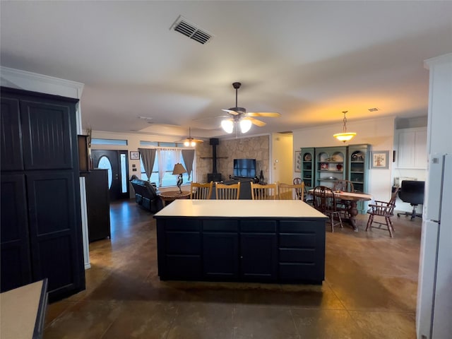 kitchen featuring white refrigerator, a center island, ceiling fan, and a wood stove