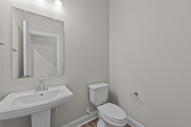 bathroom featuring a sink, baseboards, toilet, and wood finished floors