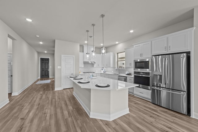 kitchen featuring light countertops, appliances with stainless steel finishes, white cabinets, a kitchen island, and a sink