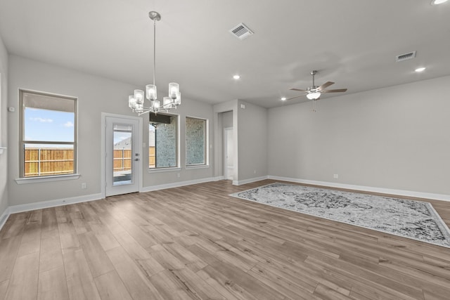 spare room with light wood-style floors, visible vents, baseboards, and ceiling fan with notable chandelier