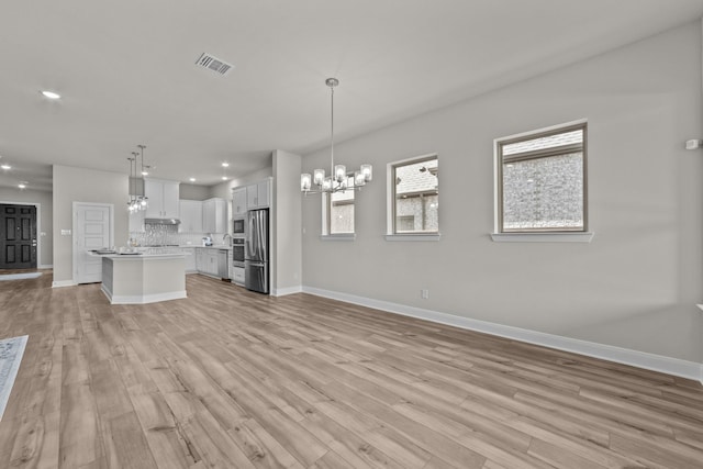 kitchen with open floor plan, light countertops, hanging light fixtures, and white cabinetry