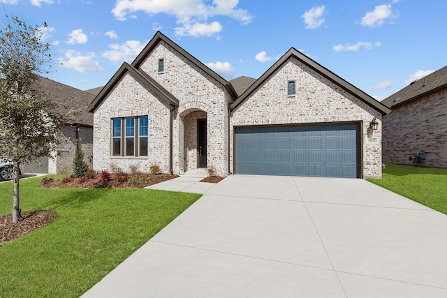 french country inspired facade featuring driveway, brick siding, an attached garage, and a front yard