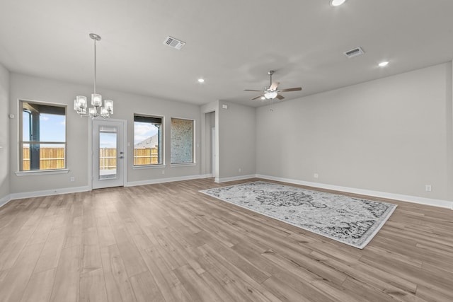 unfurnished living room featuring ceiling fan with notable chandelier, light wood finished floors, and visible vents