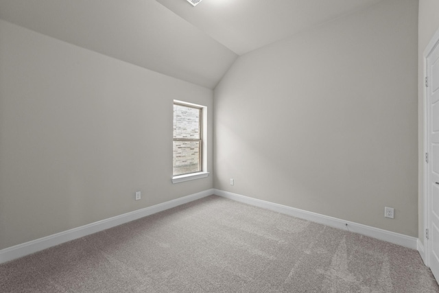 empty room featuring lofted ceiling, baseboards, and light colored carpet