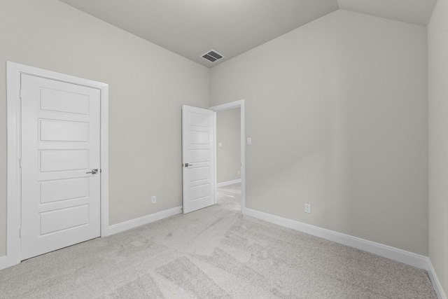 spare room featuring light carpet, baseboards, visible vents, and vaulted ceiling