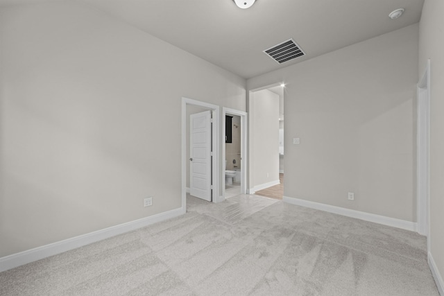 empty room featuring light carpet, visible vents, and baseboards