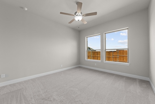 carpeted spare room with baseboards and a ceiling fan