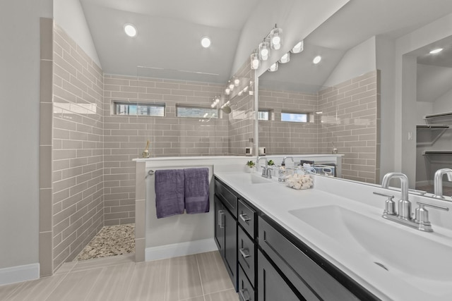 bathroom with a wealth of natural light, lofted ceiling, a sink, and walk in shower