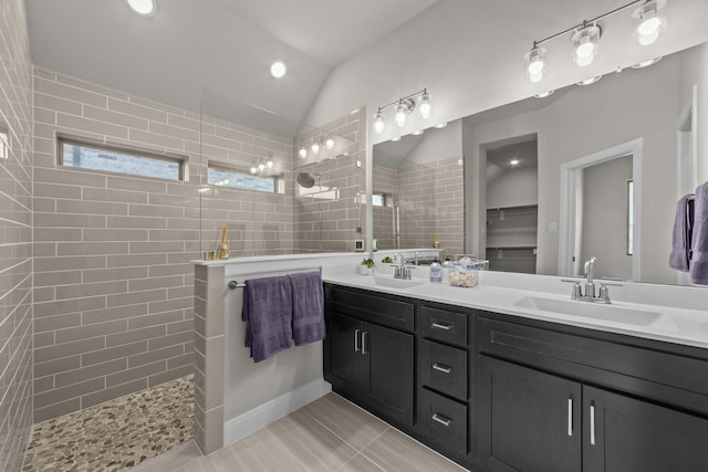 bathroom featuring lofted ceiling, double vanity, a sink, and a walk in shower