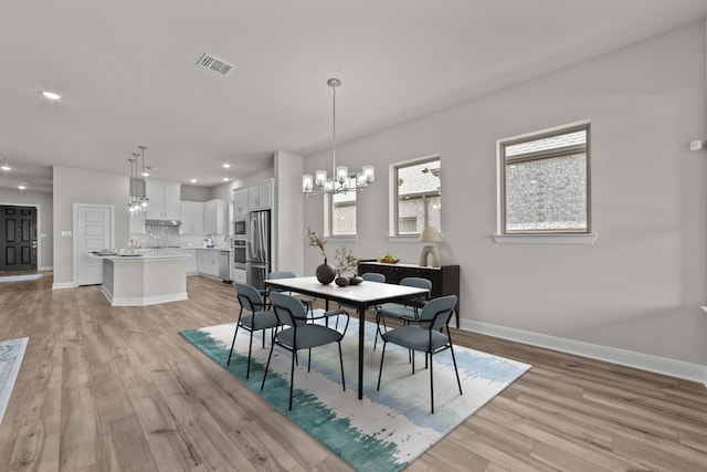 dining area featuring an inviting chandelier, baseboards, visible vents, and light wood-style floors