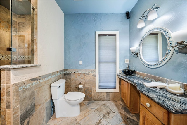 bathroom featuring tile walls, toilet, vanity, and a tile shower