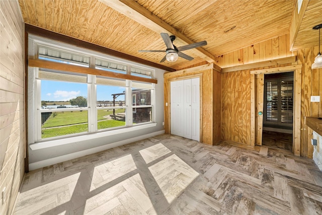 unfurnished bedroom with ceiling fan, wood walls, beam ceiling, wood ceiling, and a closet