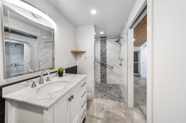 bathroom with a tile shower and vanity