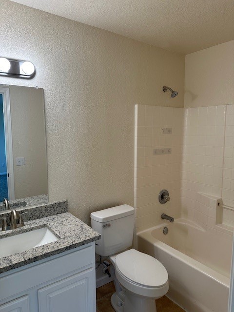 full bathroom featuring vanity, shower / bath combination, a textured ceiling, and toilet