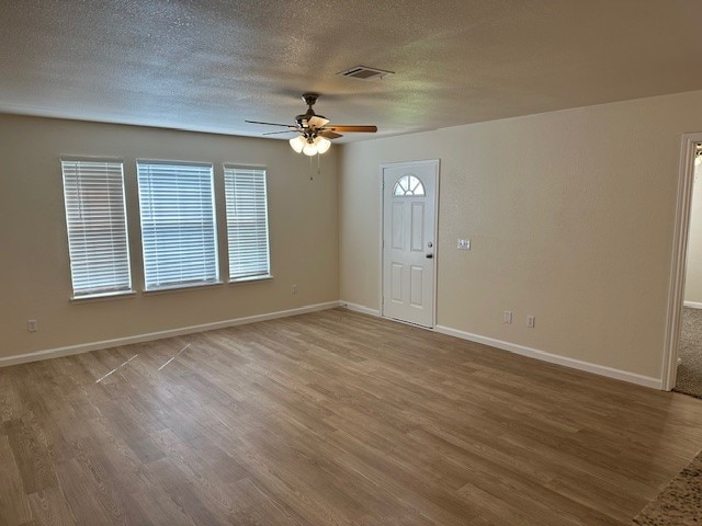 spare room with ceiling fan, light hardwood / wood-style flooring, and a textured ceiling