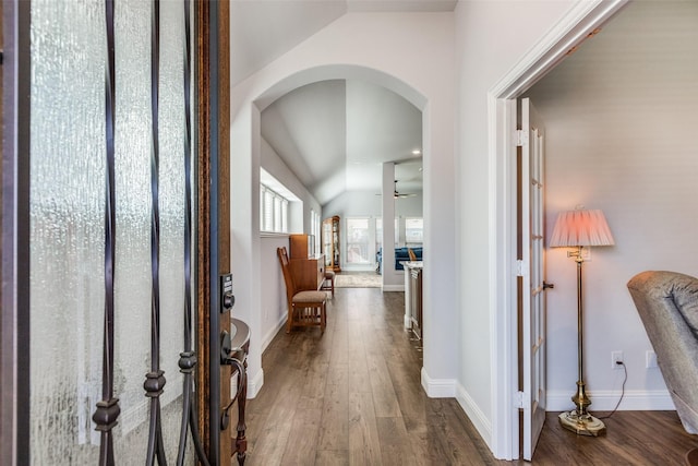 corridor with wood-type flooring and vaulted ceiling