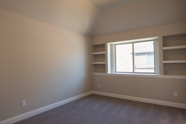 carpeted empty room with built in shelves and lofted ceiling