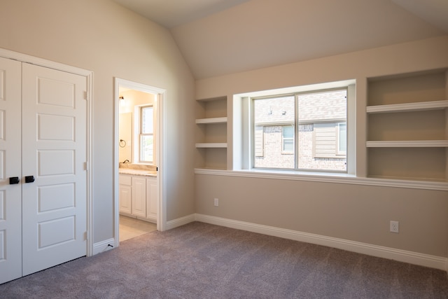 unfurnished bedroom with connected bathroom, light colored carpet, and lofted ceiling