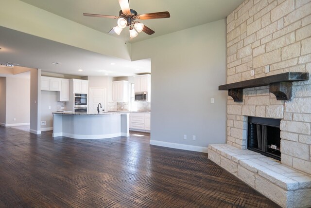 unfurnished living room with sink, ceiling fan, dark hardwood / wood-style flooring, and a fireplace