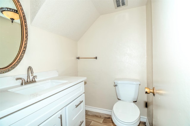 bathroom with vanity, hardwood / wood-style flooring, toilet, and lofted ceiling