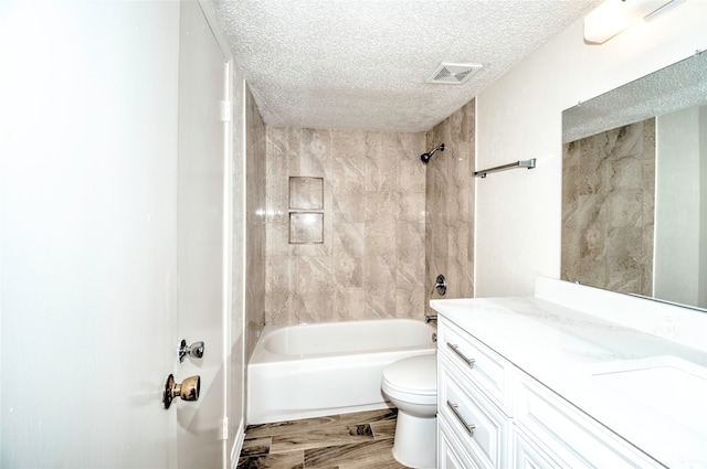 full bathroom with vanity, hardwood / wood-style flooring, tiled shower / bath combo, toilet, and a textured ceiling