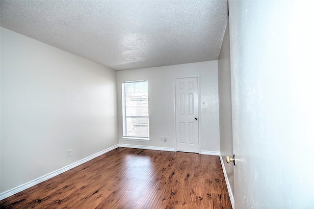 unfurnished room with wood-type flooring and a textured ceiling