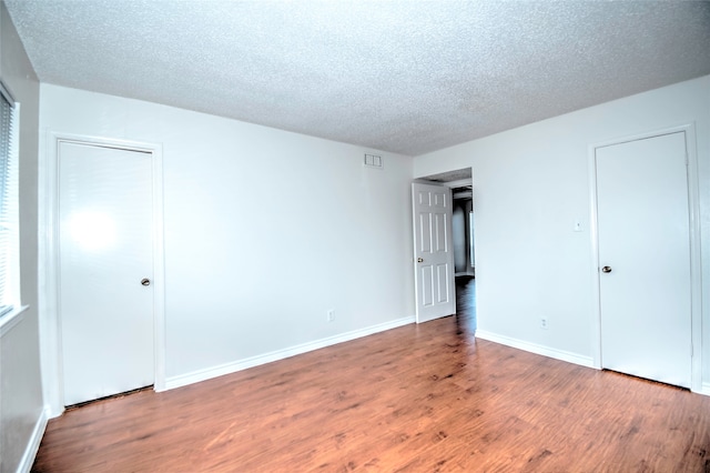 unfurnished bedroom featuring wood-type flooring and a textured ceiling