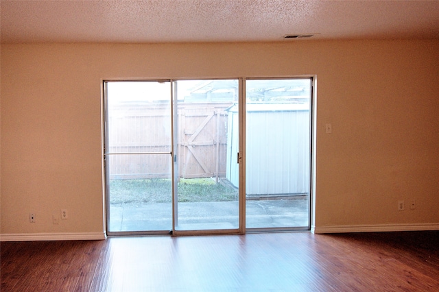 spare room featuring wood-type flooring and a textured ceiling