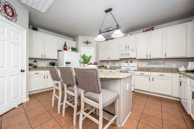 kitchen featuring white appliances, a kitchen breakfast bar, decorative light fixtures, a kitchen island, and white cabinetry