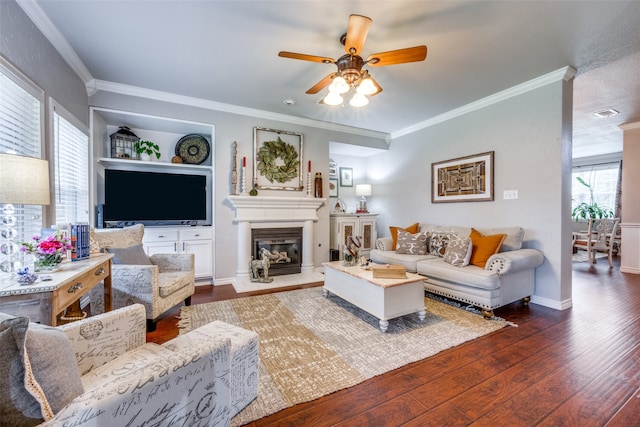 living room featuring a healthy amount of sunlight, crown molding, ceiling fan, and dark wood-type flooring