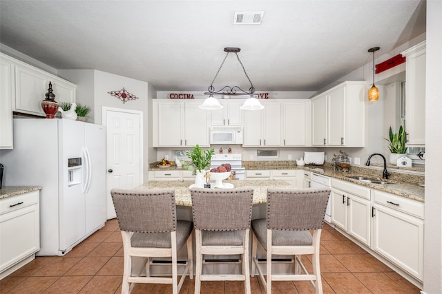 kitchen featuring pendant lighting, a breakfast bar, white appliances, sink, and light stone counters