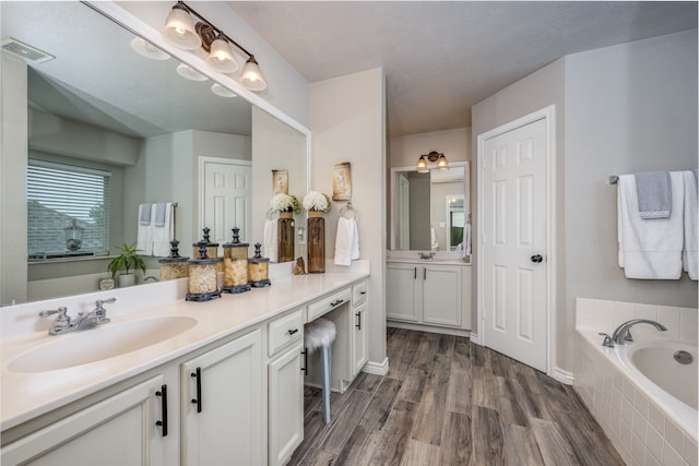 bathroom featuring hardwood / wood-style floors, vanity, and tiled bath