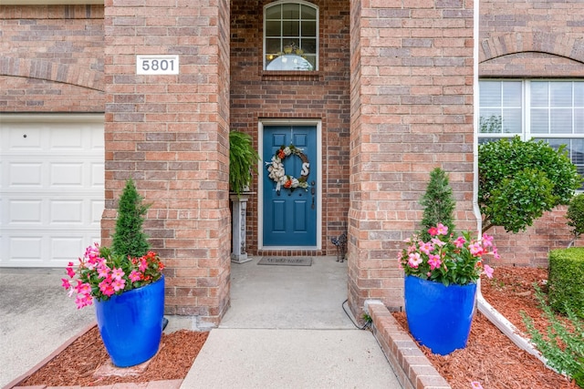 view of exterior entry with brick siding and an attached garage