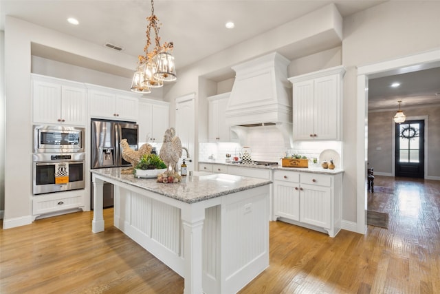2005 Tremont Blvd, Mckinney, TX 75071 - kitchen featuring appliances with stainless steel finishes, custom exhaust hood, white cabinetry, light wood-style flooring, and recessed lighting